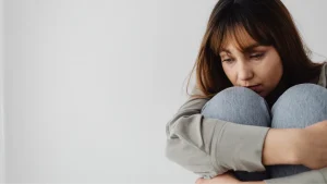 Behandling af angst. Billede af dame der sidder på hug og ser bedrøvet ud.
